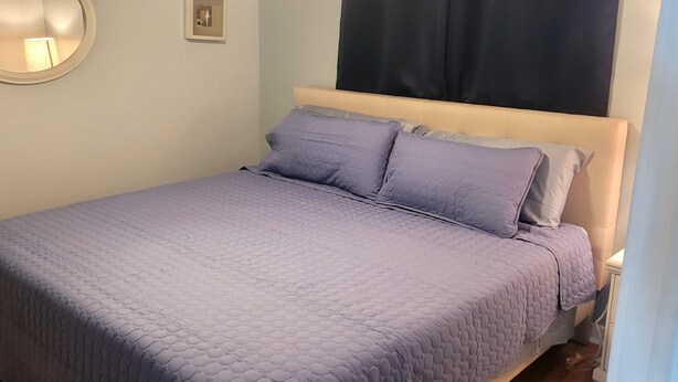 A bed with a quilted cover, a bedside table, a wall-mounted mirror, and a framed picture. - 50 gas discount applied to rates for weeks in August! Clean condo-sandy beach (Myrtle Beach)