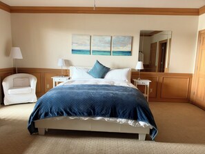 A hotel room with a large bed, two bedside tables, a chair, and a painting on the wall.