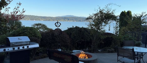 Lakeside patio with fire pit, grill, and serene water views