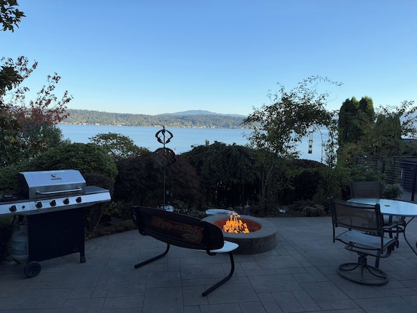 An outdoor patio with a grill, a fire pit, and seating.