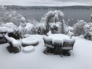 A snow-covered outdoor seating area with a view of a lake and forest. - Lakefront 3BR on Lake Sammamish, Bellevue: Hot Tub, Peloton (Bellevue)