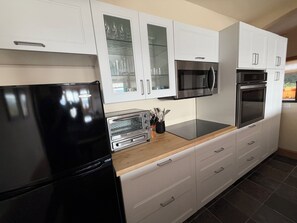 A modern kitchen with white cabinets, a black refrigerator, a microwave, an oven, and a toaster.