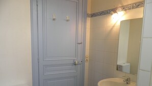 Ein Badezimmer mit weißer Tür, einem Waschbecken und einem Spiegel.