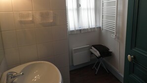 Ein Badezimmer mit weißem Waschbecken, einem Fenster mit durchsichtigen Vorhängen, einem Heizkörper und einem Handtuchhalter.