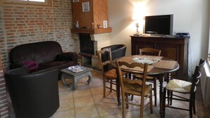 Ein gemütliches Wohnzimmer mit Kamin, Fernseher und Essbereich mit Holzmöbeln.