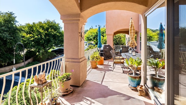 Ein Balkon mit Topfpflanzen, Gartenmöbeln und Blick auf die umliegende Grünfläche.