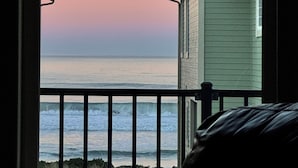 Une vue depuis un balcon donnant sur l’océan au coucher du soleil.