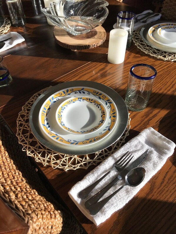 A wooden dining table set with plates, cutlery, and a glass of water.