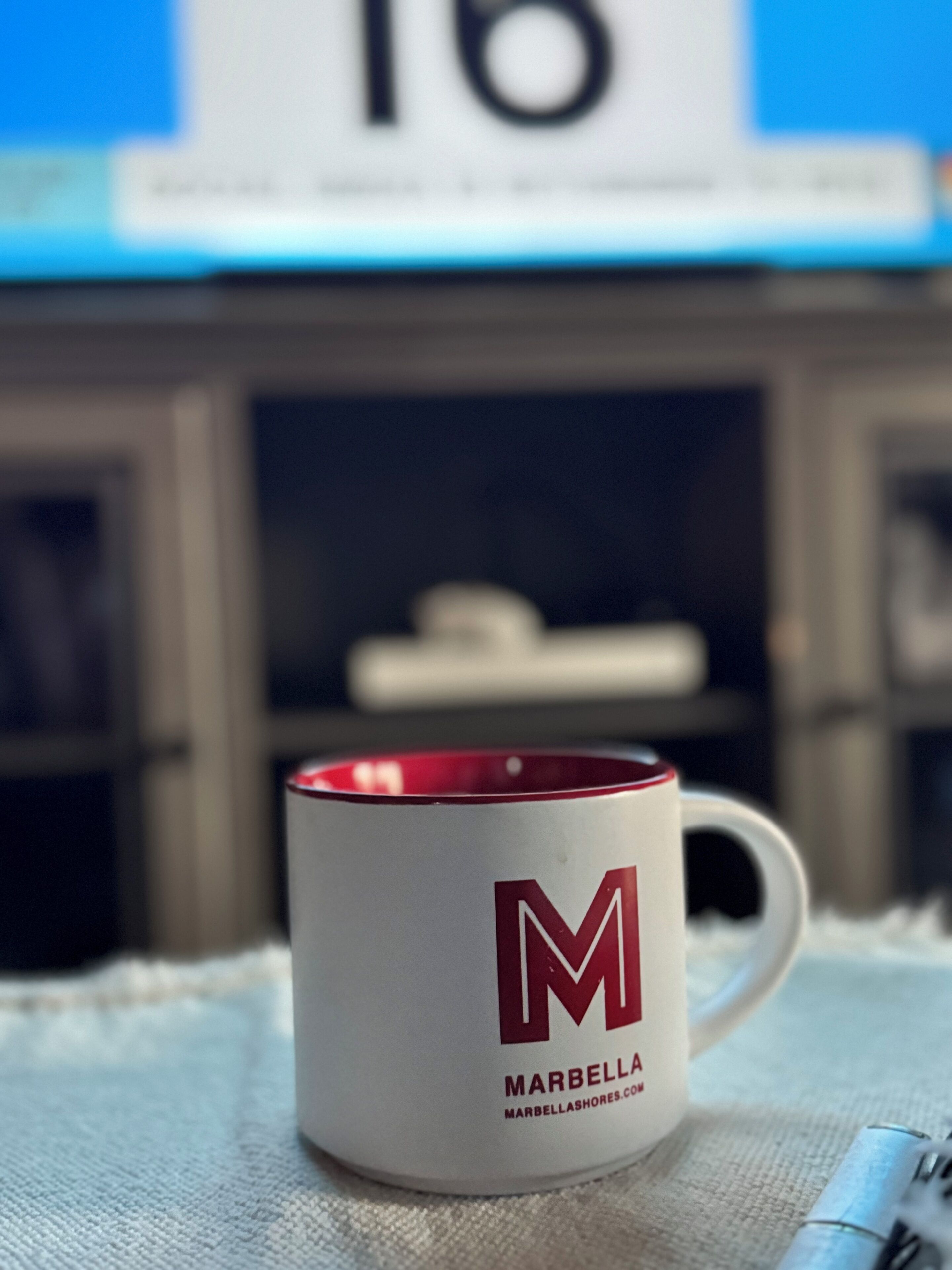A white mug with a red interior and a large 'M' logo, labeled 'MARBELLA'.