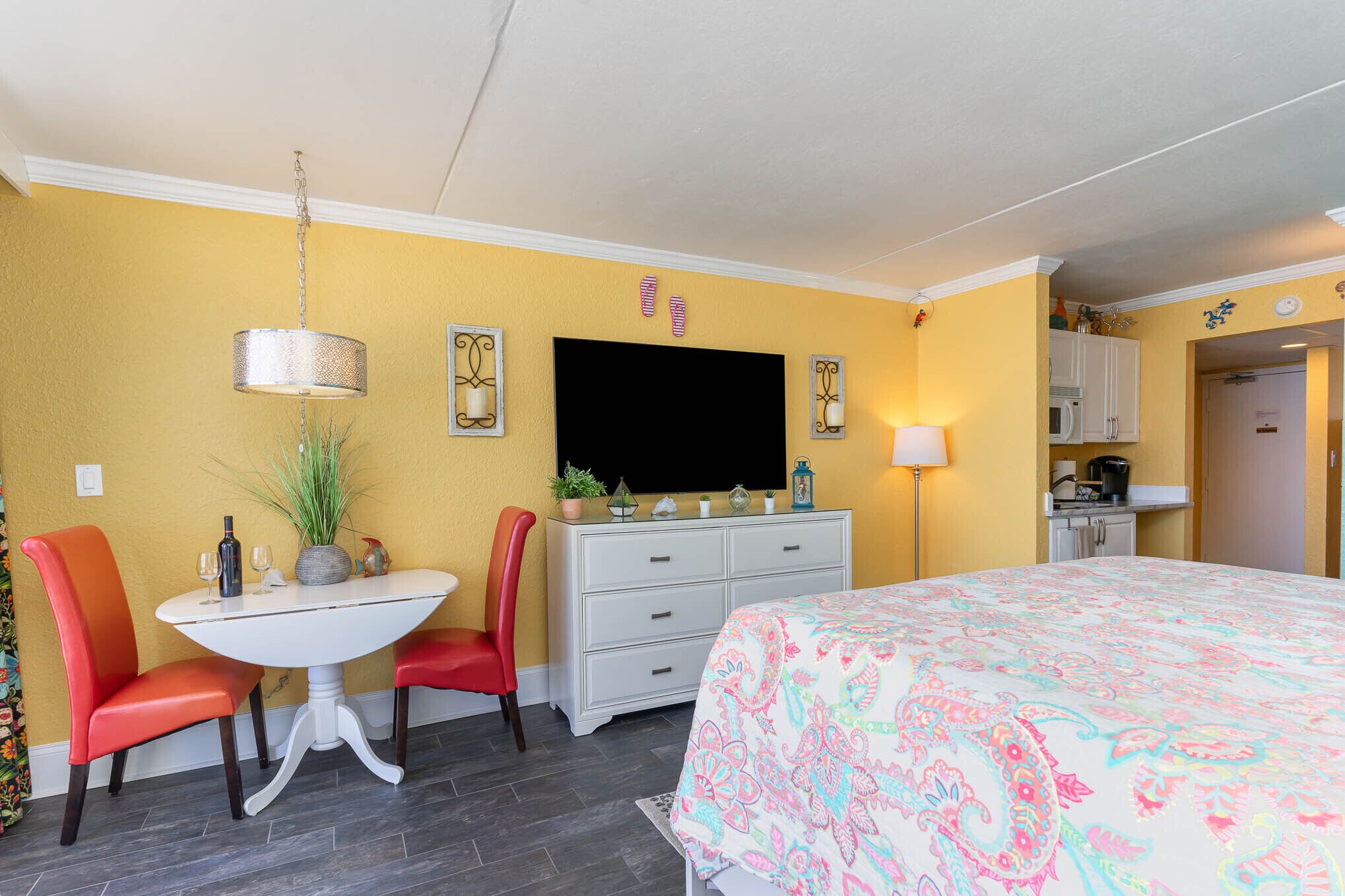 Una stanza con un letto, un tavolo da pranzo con sedie, una televisione, un comò e un forno a microonde.