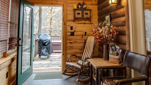 A wooden cabin interior with a ceiling fan, a dining table with chairs, a fireplace, and a view of the outside deck. - 5 BR Log Home - 5 Min/2.7miles to TIEC - with a Hot Tub on 18 acres "Creekside"  (Rutherfordton)