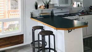 Una cocina moderna con una isla central, taburetes de bar, una araña y vistas al exterior.