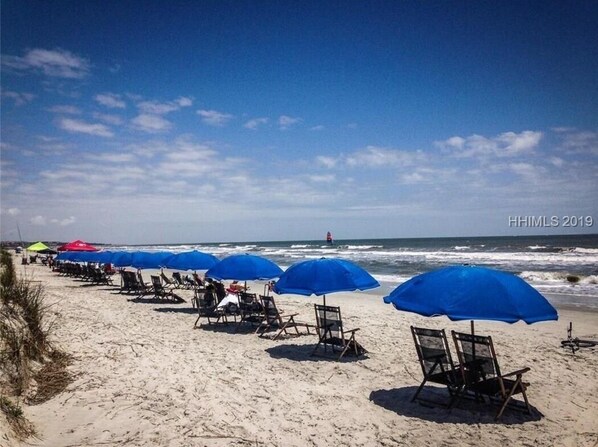 Relax on the beach with comfortable chairs and shaded umbrellas, overlooking the ocean.