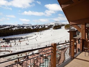 A ski resort with a view of a snowy mountain, a ski lift, and a pool area.