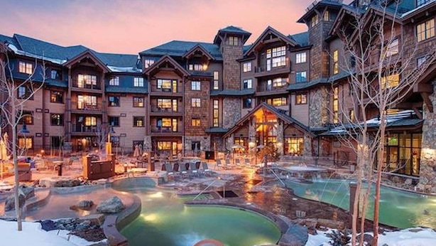 A multi-story lodge with a central courtyard featuring a hot tub and a small pool, surrounded by snow. - Spacious Luxury Two-Bedroom at Grand Lodge at Peak 7! (Breckenridge)