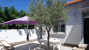 An outdoor patio with a table and chairs, a purple umbrella, and a tree. - House for 6 pers. very close to the sea and shops (Agde)