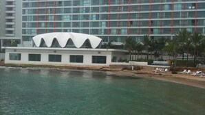 Un hotel de diseño moderno, con un edificio grande que destaca por una estructura cúpula blanca y una fachada de varios pisos con detalles en rojo.