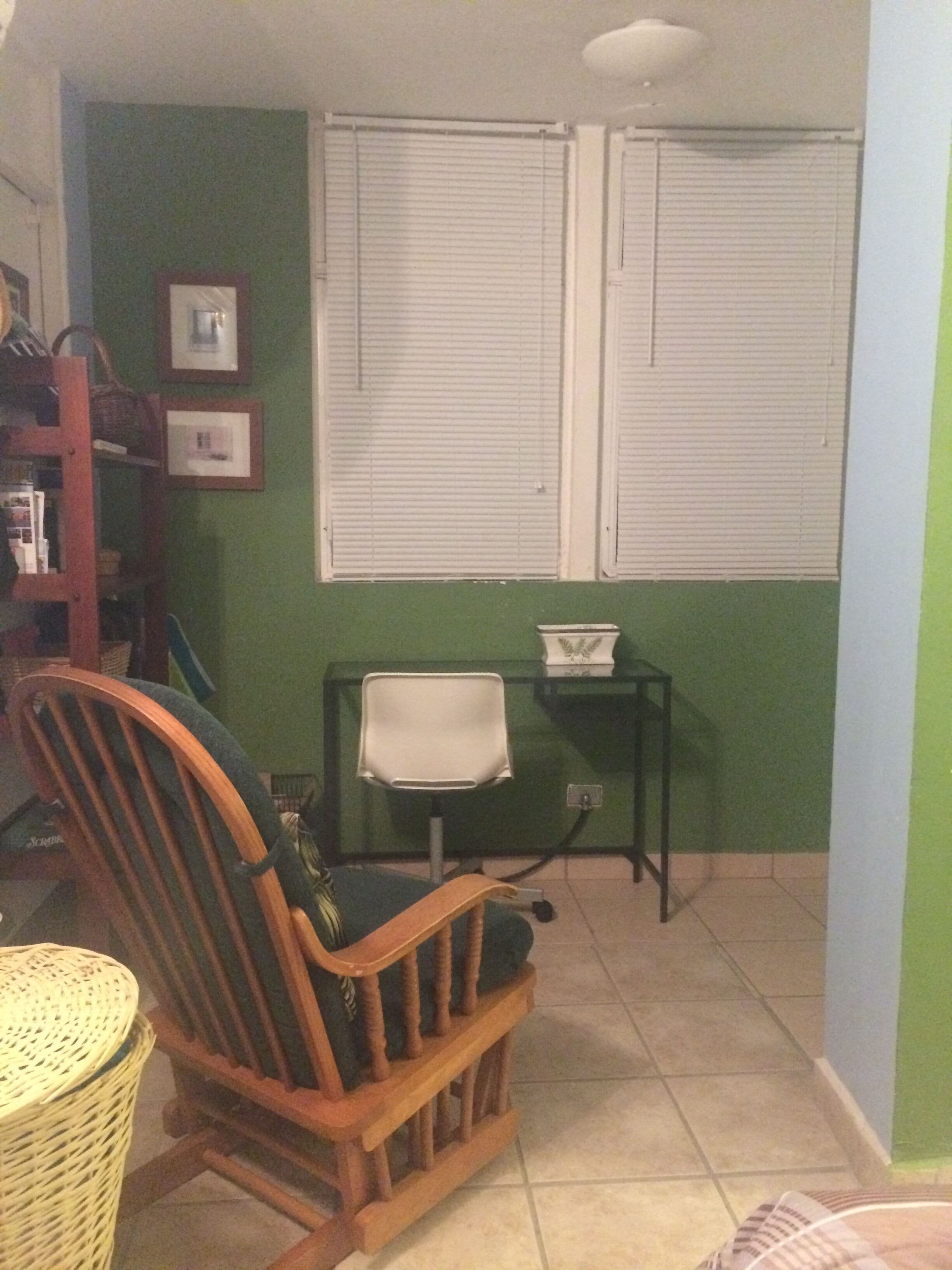Una habitación con una silla de madera, una mesita pequeña y una ventana con persianas.