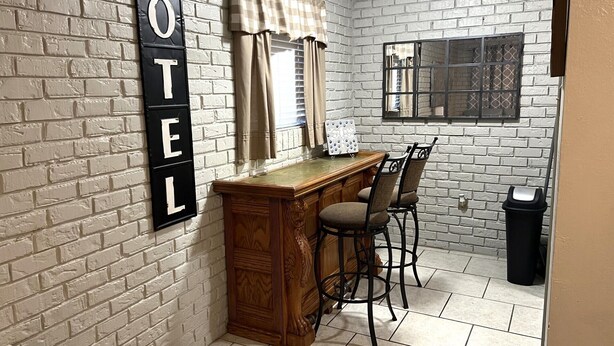 A corner room with a brick wall, a wooden desk with two chairs, a window with blinds, and a trash bin. - SUPER SUMMER SAVINGS!! ;:HOT PROPERTY (baton rouge)