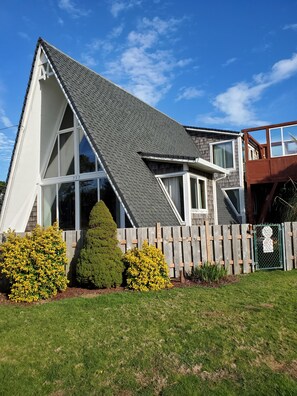 Ein modernes Haus mit Satteldach, großen Fenstern und einem Holzzaun.