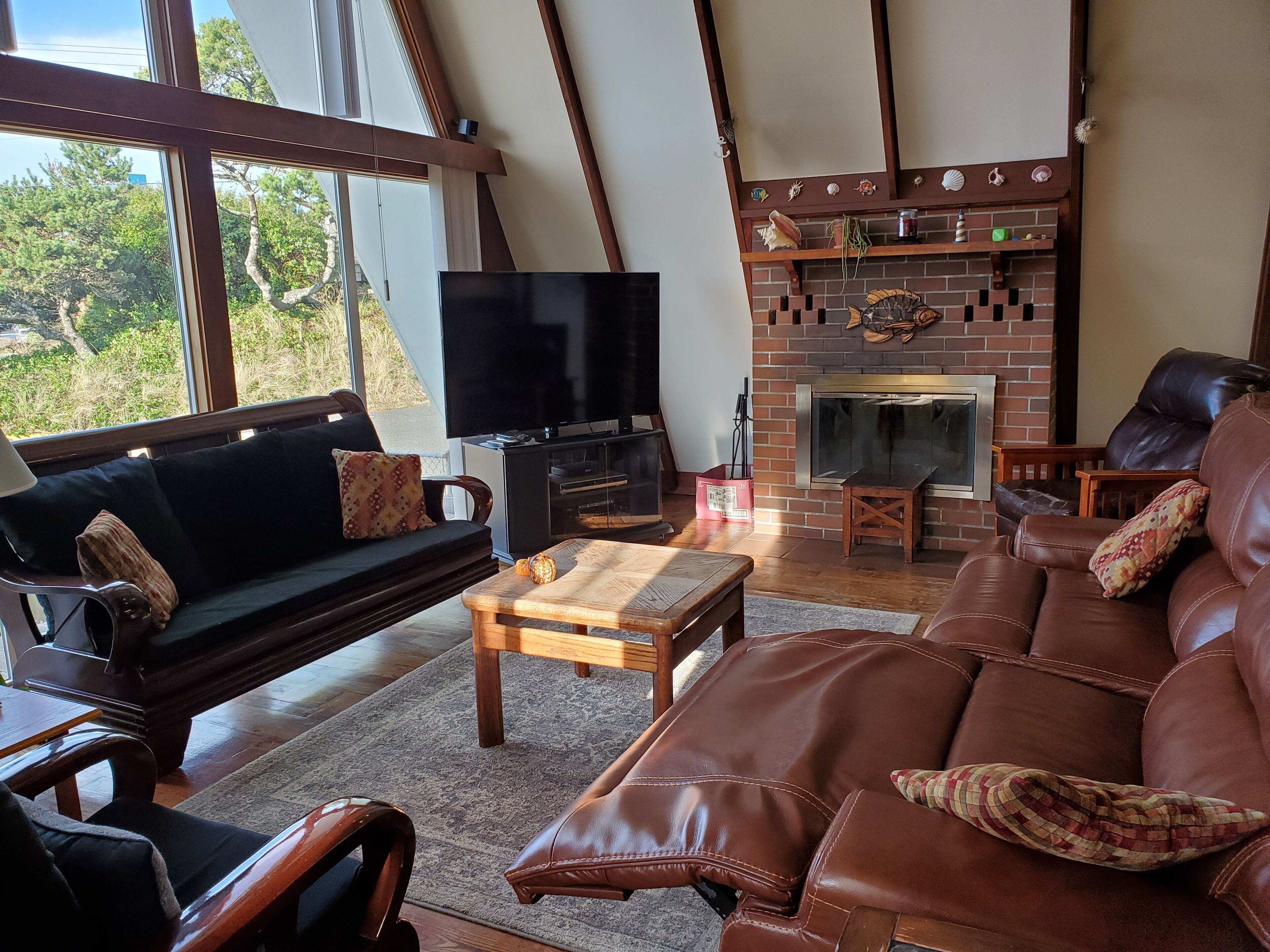 Una sala de estar acogedora con un sofá, un sofá de cuero, un televisor y una chimenea.