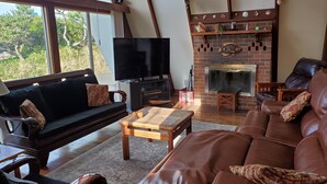Ein gemütliches Wohnzimmer mit einer Couch, einem Ledersofa, einem Fernseher und einem Kamin.
