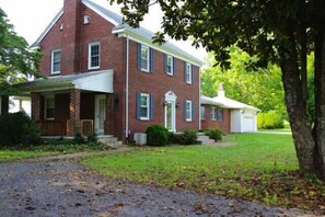 A two-story brick house with a front porch, a garage, and a well-maintained lawn.