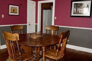 A dining room with a round wooden table and six chairs.