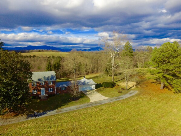A house with a brick exterior, a large front yard, and a view of mountains in the background.