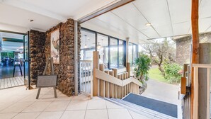 An indoor entrance with a stone wall, a wooden staircase, and a view of the outdoors. - Spacious Studio Beach Chic, Walk to Sandy Napili Bay-Napili Shores C116 (Lahaina)