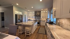 A modern kitchen with a central island, stainless steel appliances, and a view to the outside.