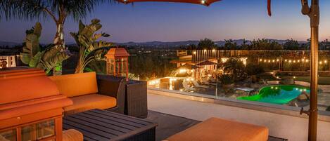 An outdoor patio with wicker furniture, a pool, and string lights.