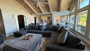A spacious living room with a large sectional sofa, a wooden coffee table, and a cozy rug.