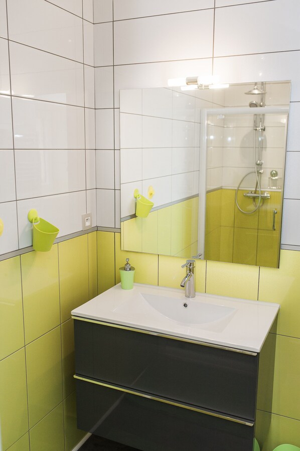 A bathroom with a white sink, a mirror, and a shower.