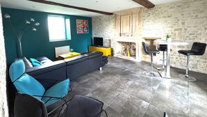 A living room with a sectional sofa, a television, a fireplace, and a dining area with bar stools.