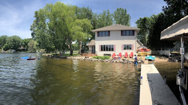A lakeside house with a dock, surrounded by trees and a clear sky. - Lakefront Family Getaway! Pontoon Rentals-Kayak-Pedal Boat-Fire Pit-Sandy Beach (Lindstrom)