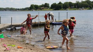 A lake with a dock and people in the water. - Lakefront Family Getaway! Pontoon Rentals-Kayak-Pedal Boat-Fire Pit-Sandy Beach (Lindstrom)