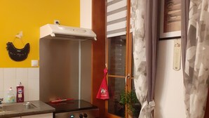 Une cuisine équipée d’une cuisinière, d’un four et d’une fenêtre avec des rideaux.