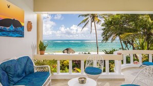 A balcony with white wicker furniture, a view of the ocean, and a painting of a whale. - Cabarete - on Kite Beach - Luxury Beachfront Condo w Gardens, Pool & Internet   (caberate)