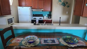 A kitchen with wooden cabinets, a white refrigerator, a stove, and a microwave. There is a sink with a faucet and a decorative wall piece above it. - Port Aransas condo in the heart of town' LP217B (Port Aranasas)