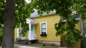A yellow house with a white porch, a front door with a wreath, and a window with a flower box.