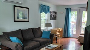 A living room with a sofa, a wooden coffee table, a lamp, and a TV.