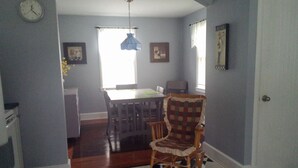 A dining area with a checkered floor, a rocking chair, and a dining table.
