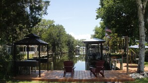 Une terrasse au bord de la rivière, agrémentée de deux fauteuils Adirondack, d’un belvédère et d’un drapeau américain.