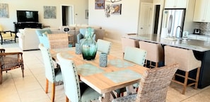 A spacious living area with a dining table, comfortable seating, a kitchen with modern appliances, and a flat-screen TV.