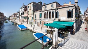 A canal with boats docked, buildings with traditional architecture, and a staircase leading down to the water.