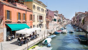 A canal lined with colorful buildings, boats docked along the water, and outdoor seating for people to enjoy the view.