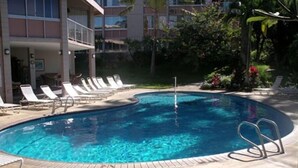 A swimming pool with lounge chairs and a building in the background. - 2 bdrm 2 Bath Condo with Partial Ocean Views, Steps away from Kamaole III Beach  (Kihei)