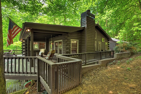 A log cabin with a deck, a flag, and a chimney. - LAKEFRONT, MTN VIEW, HOT TUB, POOL TABLE, FIREPIT, PROJECTOR, DOGS OK, 3BD AVAIL (Blue Ridge)
