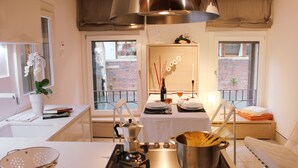 A kitchen with a stove, sink, and a dining area with a table set for two. - Charming, views Of Canals, Gondolas, Church Of The Miracoli (Venezia)